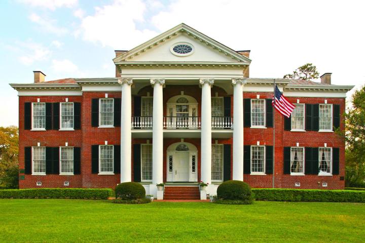 a large brick building with a grassy field