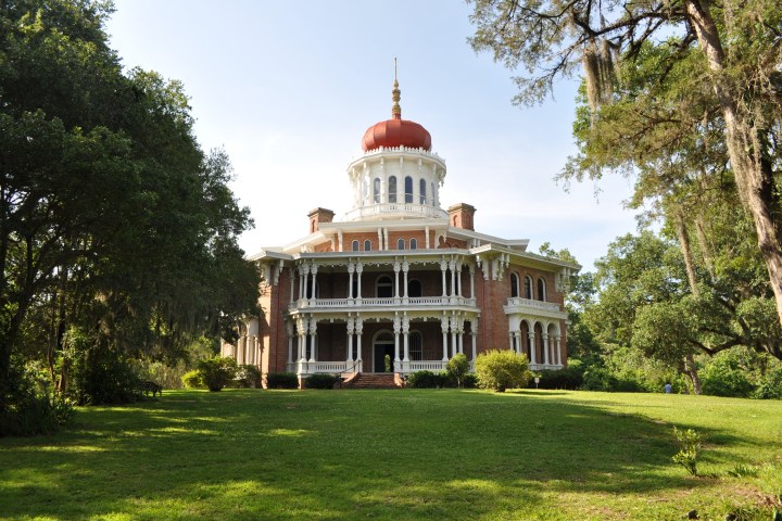 a large building with a grassy field with Yaquina Bay Light in the background