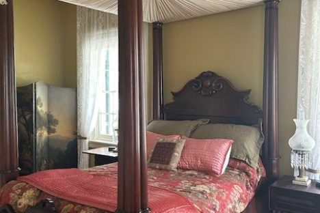 Vintage bedroom with canopy bed, floral bedding, and antique decor.