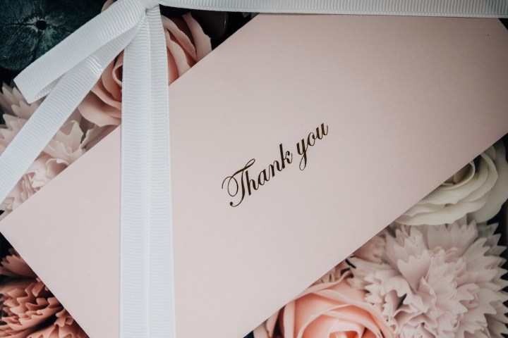 Pink card with 'Thank you' on flowers, tied with white ribbon.